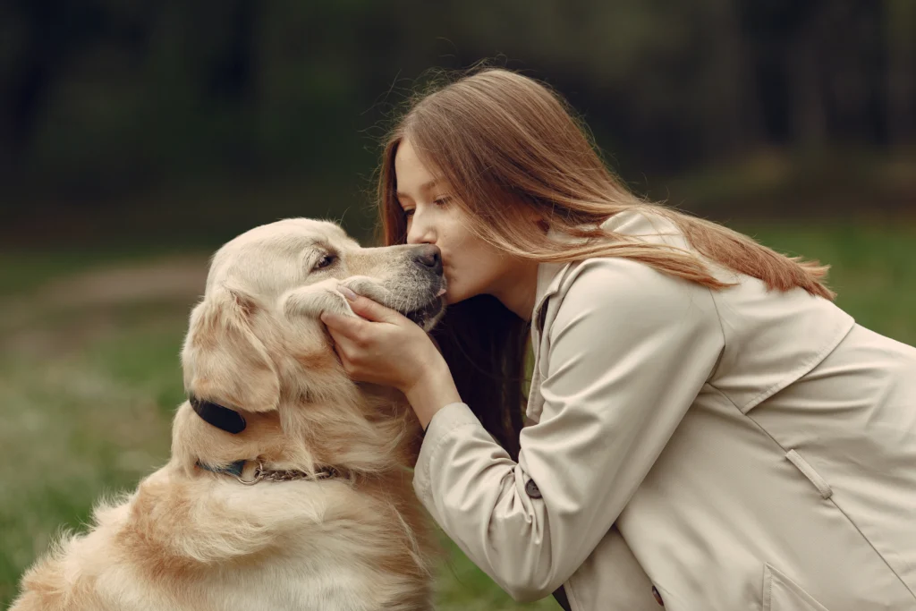 Menina sorridente abraçando um Golden Retriever, simbolizando amizade e doçura entre cães e crianças.