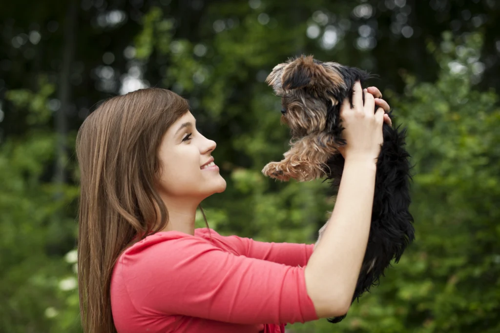 Tutor acariciando um filhote de cachorro, simbolizando a escolha entre macho e femea